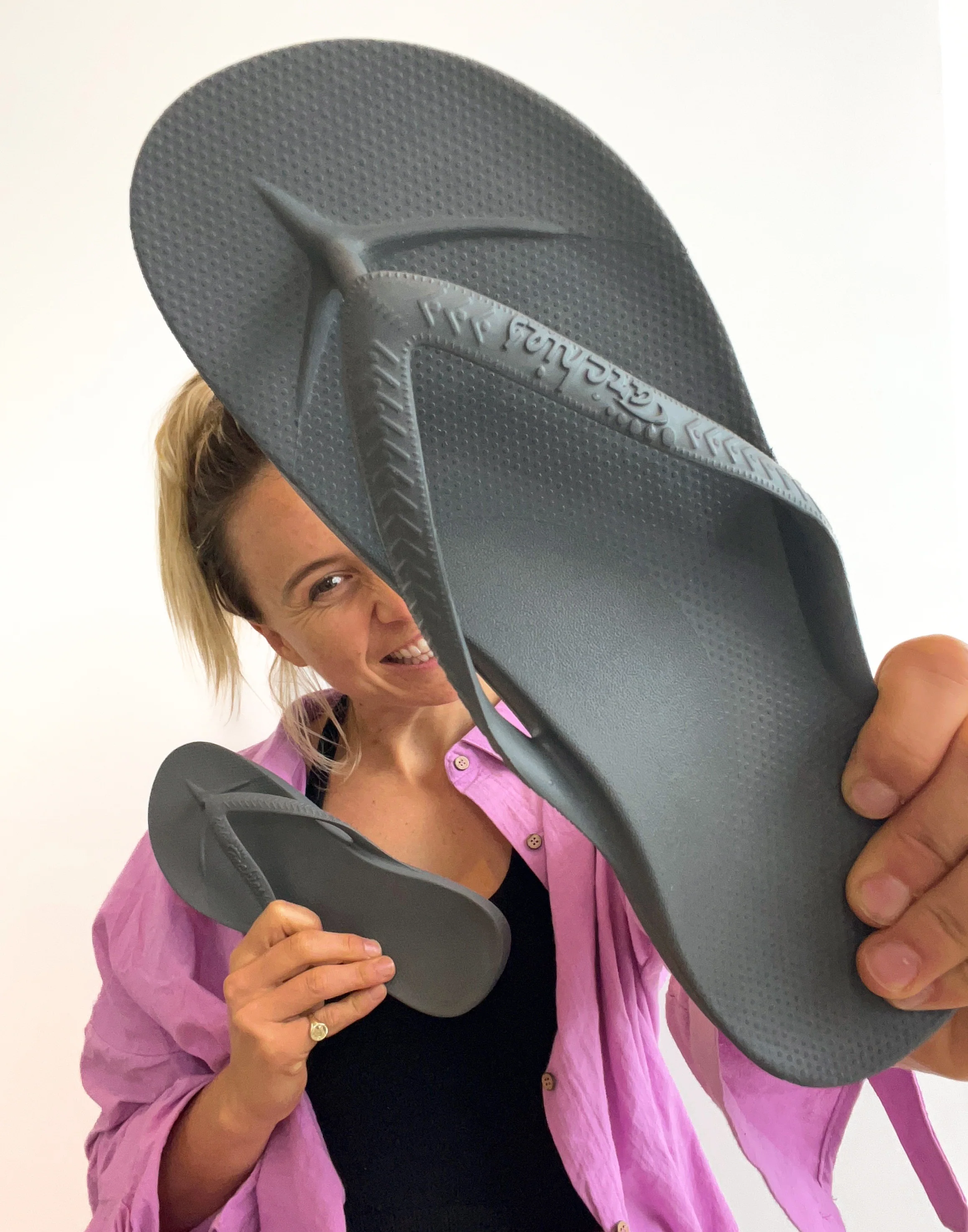 Archies arch support thongs in a charcoal style pictured being held by a woman