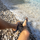 Archies arch support thongs in a navy style pictured being worn by a man at a stony shoreline